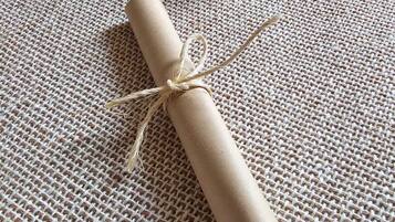 A rolled-up piece of paper tied with a string on a textured surface.