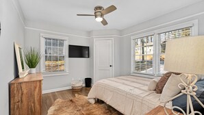 A bedroom with a bed, a ceiling fan, a TV, and windows with blinds. - The Lockheed Lady - 3/2 Renovated Ranch in Marietta (Marietta)
