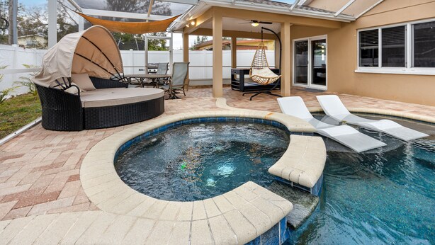 Een achtertuin met een jacuzzi, buitenzitplaatsen en een overdekt terras.
