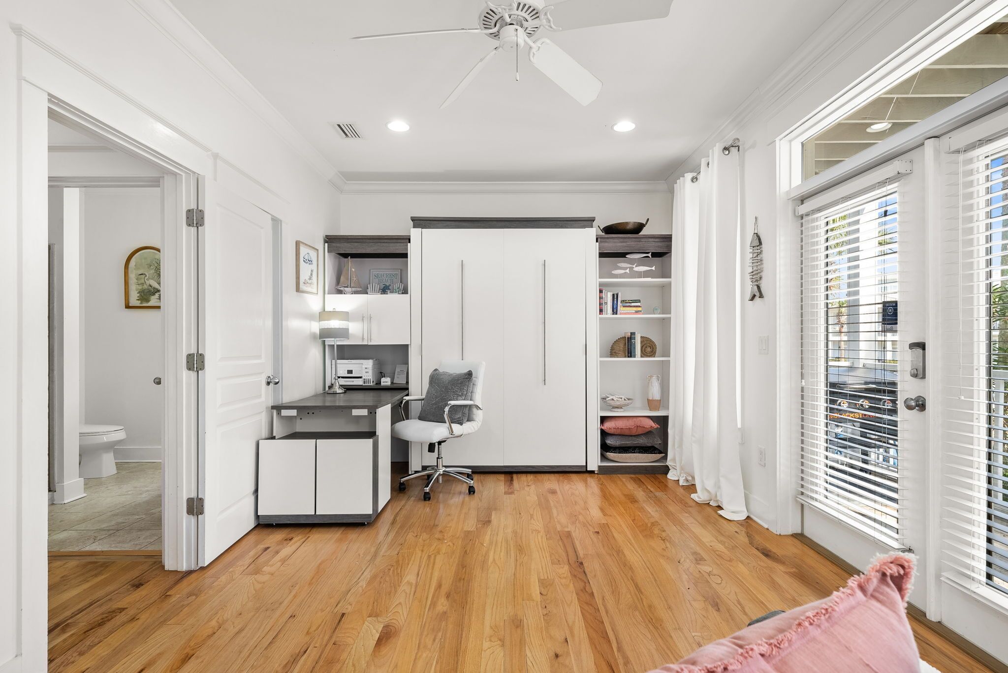 A modern kitchen with white cabinets, a black countertop, and a ceiling fan.