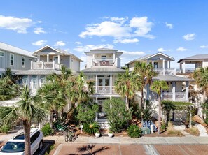 A beachfront property with multiple-story houses, a covered walkway, and palm trees. - GORGEOUS 4/4 SLEEPS 10! GULF VIEW FROM 3rd FLOOR! NEWLY FURNISHED!!! ONE BLOCK FROM BEACH ACCESS! (Panama City Beach)