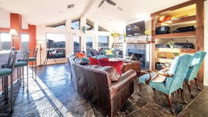 A spacious living room with a fireplace, leather sofa, and a television.