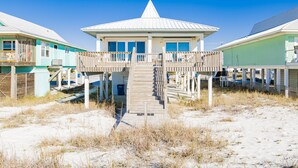 A beachfront house with a wooden deck and a covered porch. - Relaxing Beachfront Getaway | Gulf Shores Favorite (Gulf Shores)