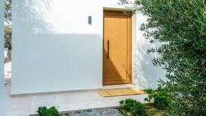 Un edificio moderno con una puerta de madera, un pequeño porche y un sendero de grava que lleva a la entrada.
