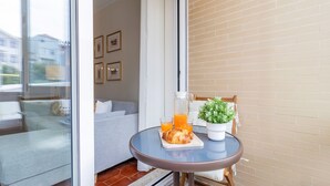 A balcony with a glass table, a potted plant, a glass pitcher, and a croissant. - Urban Retreat Porto by LovelyStay (Porto)