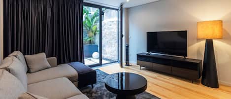 A modern living room with a sofa, a coffee table, a TV, and a lamp.