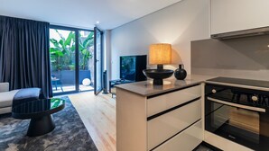 Una cocina moderna con una isla grande, un comedor con mesa y sillas negras, y una sala de estar con sofá y mesa de centro.