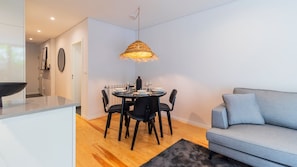 Una cucina moderna con un tavolo da pranzo per quattro persone, una sedia nera e un divano grigio.