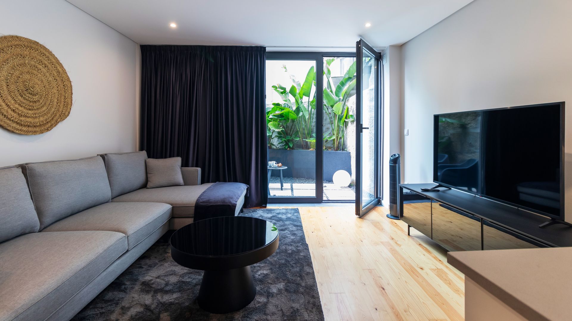 Relax in the stylish living area, where large glass doors open to a serene private patio oasis with lush greenery.
#LivingRoom #PrivatePatio #LovelyStay