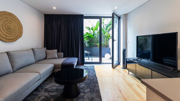 Relax in the stylish living area, where large glass doors open to a serene private patio oasis with lush greenery.
#LivingRoom #PrivatePatio #LovelyStay