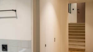 Un couloir avec un escalier en bois menant à une porte.