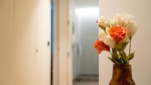 Un vase en bois orné d’un bouquet de fleurs blanches, oranges et roses, accroché au mur d’un couloir.