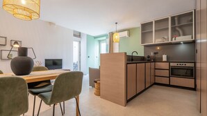 Une cuisine moderne avec des meubles en bois, un four encastré et un coin repas comprenant une table et des chaises.