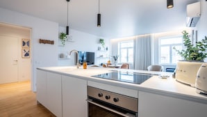 A modern kitchen with a central island, built-in oven, and a dining area with a view of the city. - Penthouse w/ City Views | Almada 551 (Porto)