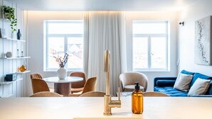 A modern living room with a round dining table, two chairs, a blue sofa, and a large window with curtains. - Penthouse w/ City Views | Almada 551 (Porto)