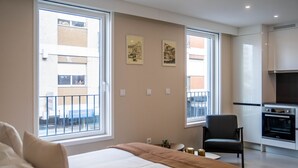 A modern hotel room with a large bed, a chair, a small table, and a kitchenette. - Gaia Retreat by LovelyStay (Vila Nova de Gaia)