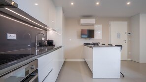 A modern kitchen with a built-in oven, a stainless steel range hood, and a flat-screen TV mounted above the counter.