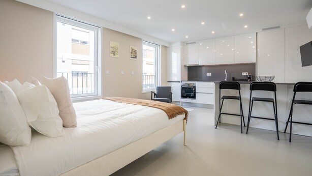A modern hotel room with a large bed, a kitchenette, and a dining area with two chairs. - Gaia Retreat by LovelyStay (Vila Nova de Gaia)