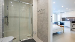 Un baño moderno con ducha de mampara de vidrio, inodoro y lavamanos.