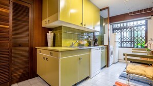 Une cuisine compacte avec des meubles de couleur jaune, un four encastré et une fenêtre donnant sur un espace verdoyant.