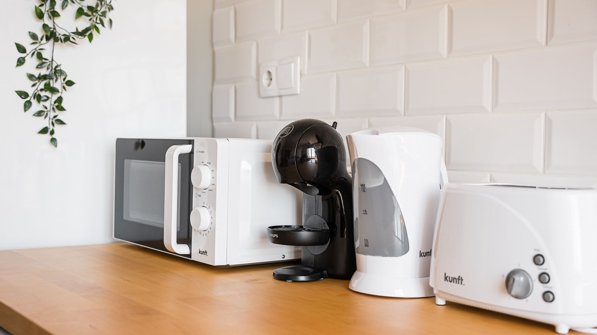 A kitchen with a microwave, coffee maker, and toaster on a wooden countertop.