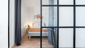 A bedroom with a bed, bedside table, lamp, and wall art.