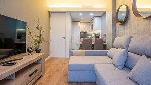 A modern living room with a sectional sofa, a flat-screen TV, and a wooden entertainment unit.