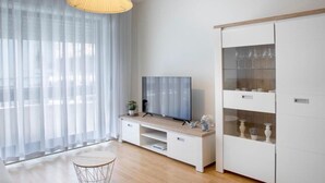 A modern living room with a flat-screen TV, a wooden coffee table, and a white cabinet with glass doors. - Belas Artes Apartment by LovelyStay (Porto)