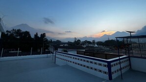 A rooftop terrace with a view of a mountain range during sunset. - Hotel Teresas Bistro Antigua (Antigua Guatemala)