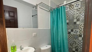 A bathroom with a white sink, toilet, and shower curtain. - Hotel Teresas Bistro Antigua (Antigua Guatemala)