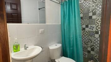 Un baño con lavamanos, inodoro y cortina de ducha blancos.