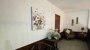 A hallway with a wooden bench, a chair, a table with a plant, and a painting on the wall. - Hotel Teresas Bistro Antigua (Antigua Guatemala)