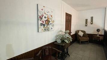 Un pasillo con un banco de madera, una silla, una mesa con una planta y un cuadro en la pared.