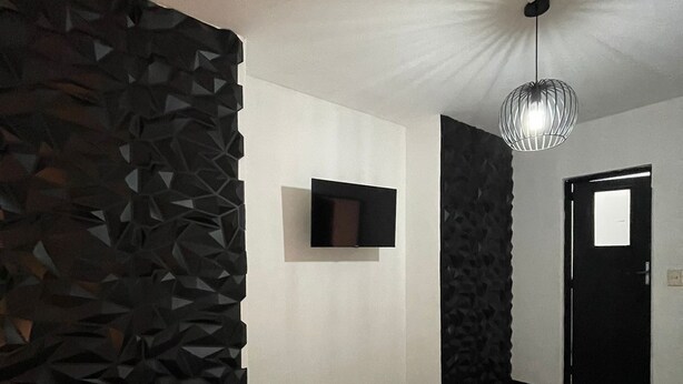 A modern hotel room with a large bed, a flat-screen TV mounted on the wall, and a unique textured wall on one side. - Hotel Teresas Bistro Antigua (Antigua Guatemala)