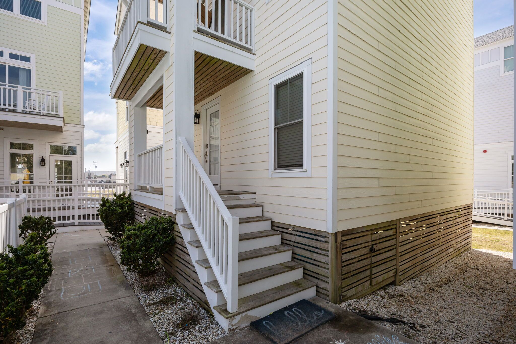 A two-story residential building with a front porch, a staircase, and a small front yard.