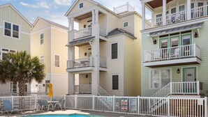 Un immeuble à plusieurs étages doté de balcons, d’une piscine et d’une clôture blanche.