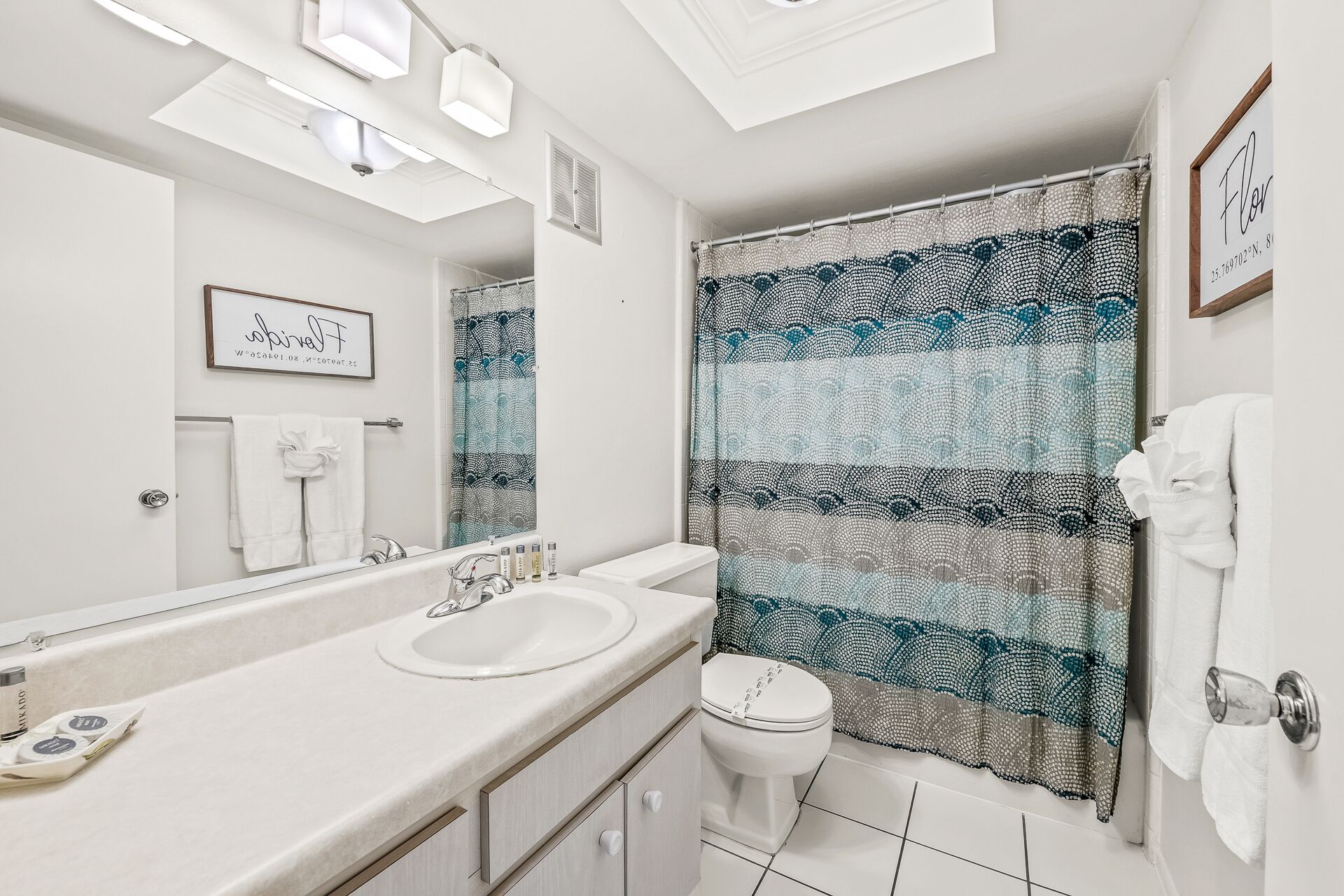 A bathroom with a white sink, a toilet, and a shower curtain with a blue and white pattern.