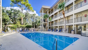 Une piscine avec des chaises longues et un bâtiment doté de balcons.
