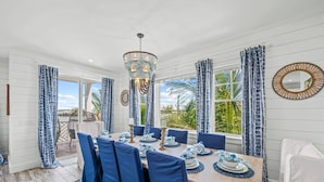 A dining area with a wooden table set for six, blue chairs, and a chandelier.