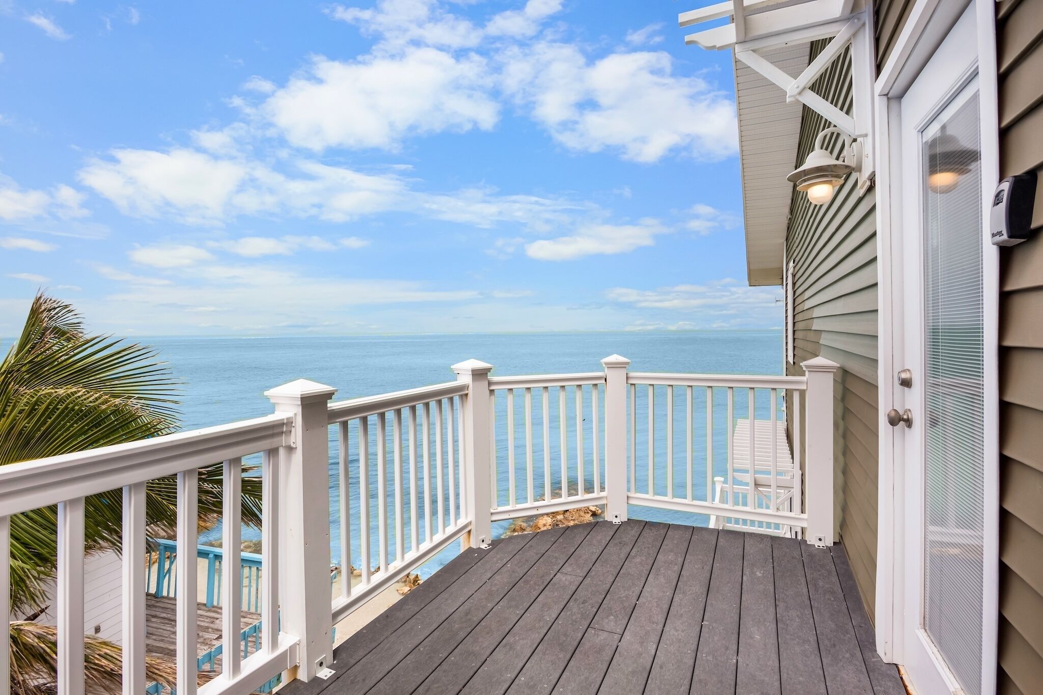 Une terrasse en bois avec une balustrade blanche donnant sur une plage.