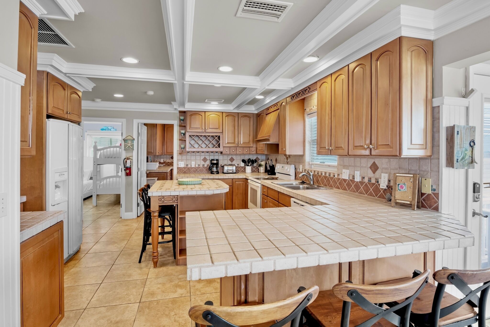 A spacious kitchen with wooden cabinets, a large island with bar stools, and a built-in oven.