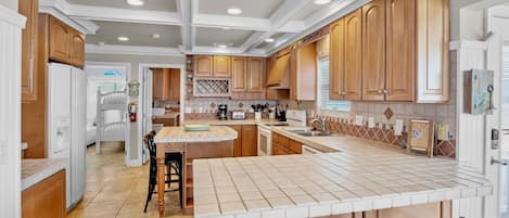 A spacious kitchen with wooden cabinets, a large island with bar stools, and a built-in oven.