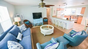 A modern living room with a blue sofa, a coffee table, and a TV. - Single-Level Beach Home, Short Walk to Sand! Close to Dining, Shopping, and More (Holmes Beach)