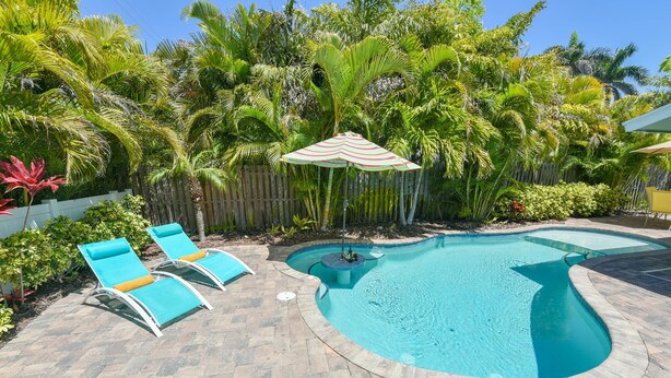A swimming pool with lounge chairs and a wooden fence. - Single-Level Beach Home, Short Walk to Sand! Close to Dining, Shopping, and More (Holmes Beach)