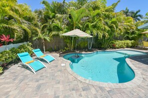 Une piscine avec des chaises longues et une clôture en bois.
