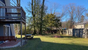 A backyard with a wooden deck, a picnic table, and a brick fire pit. - Family Retreat at Conneaut Lake, PA ideal for family fun or relaxing get- away!  (Conneaut Lake)