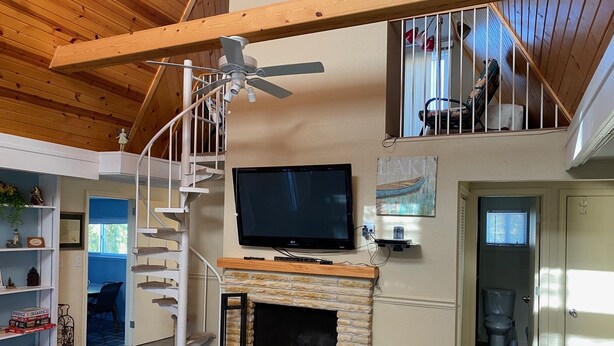 A spacious living room with a stone fireplace, a mounted TV, and a wooden ceiling. - Family Retreat at Conneaut Lake, PA ideal for family fun or relaxing get- away!  (Conneaut Lake)