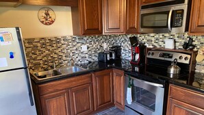 A kitchen with wooden cabinets, a stainless steel refrigerator, a microwave, a stove, and a sink. - Family Retreat at Conneaut Lake, PA ideal for family fun or relaxing get- away!  (Conneaut Lake)