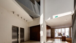 Un hall d’entrée spacieux avec un plafond haut, une grande porte en bois et une vue sur l’extérieur grâce à de larges fenêtres.