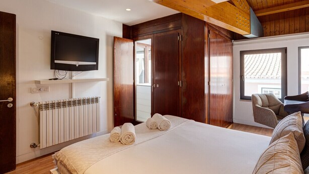 Une chambre à coucher avec un lit, une télévision, une armoire en bois et un radiateur.